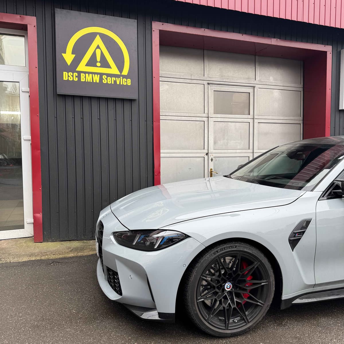 Біла BMW M біля вивіски DSC